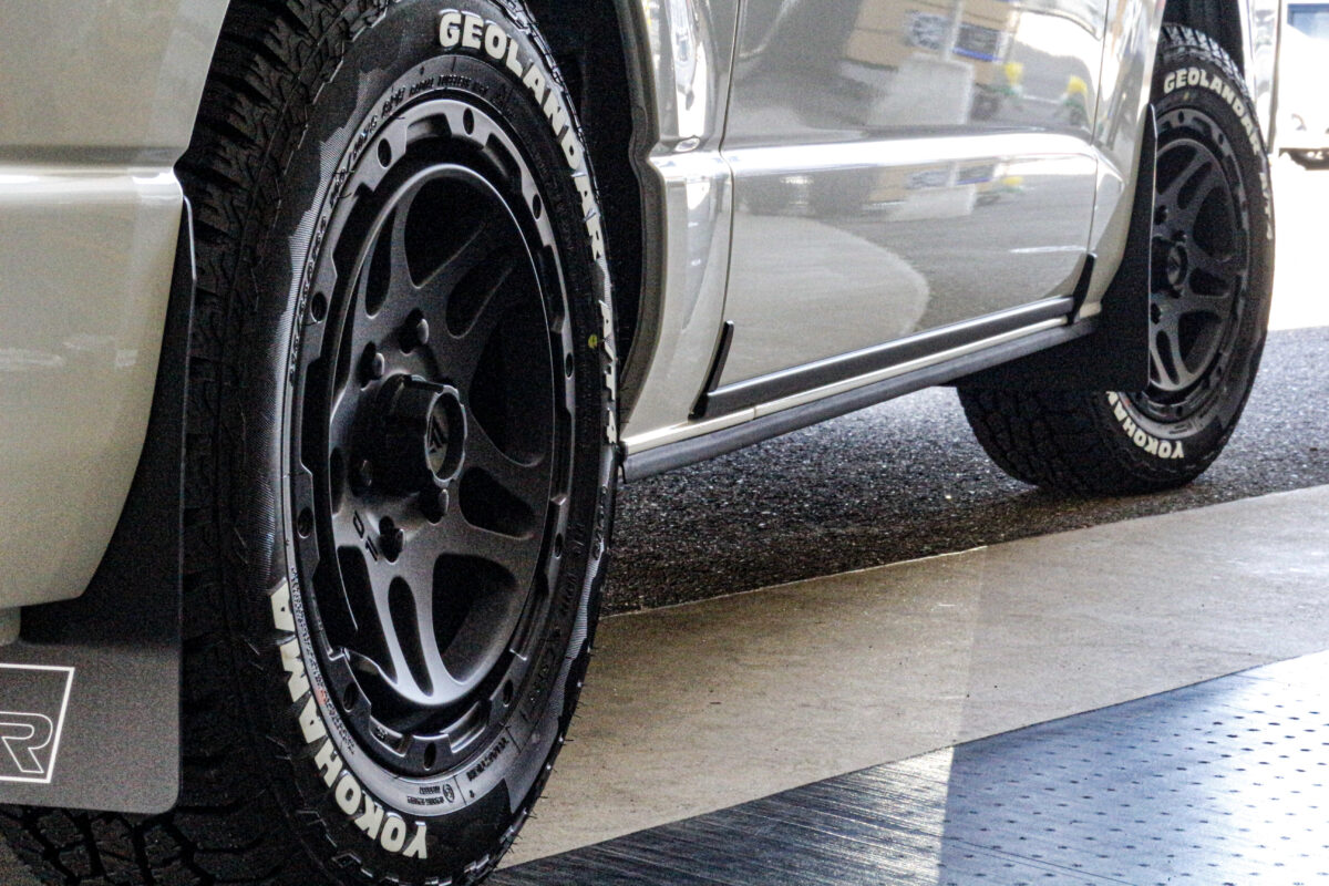 トヨタ ハイエースに装着されたDELTAFORCE OVERLANDERとジオランダーA/T4のクローズアップ。マットブラックのホイールとタイヤのサイドブロックが無骨さを強調。